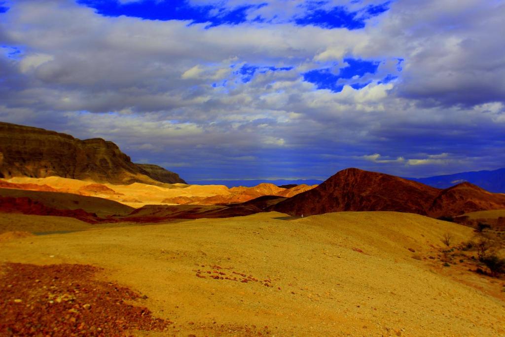 a desert scene with mountains and a cloudy sky at Park Timna in Eilat