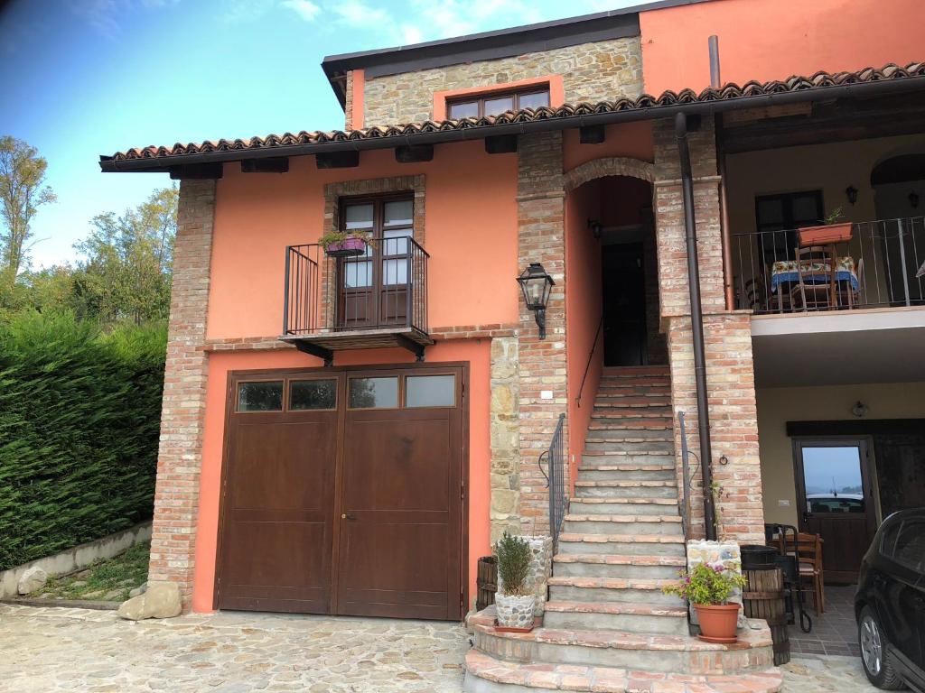 una casa con una puerta de garaje marrón y escaleras en Agriturismo La Cà Veja, en Monforte dʼAlba