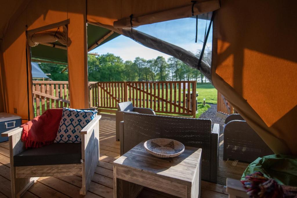 a porch with a table and chairs on a deck at Lapwing Safari Tent in Cheltenham