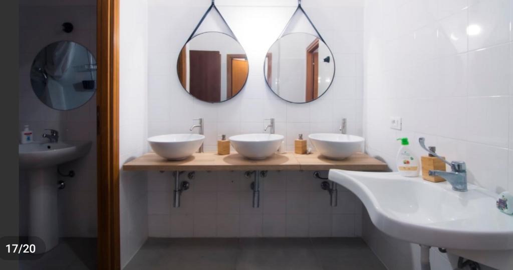 a bathroom with two sinks and two mirrors at Hostelleria in Trapani