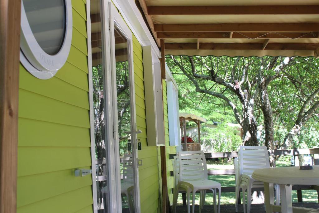 Casa verde con sillas blancas y mesa en Camping Le Ventadour en Meyras