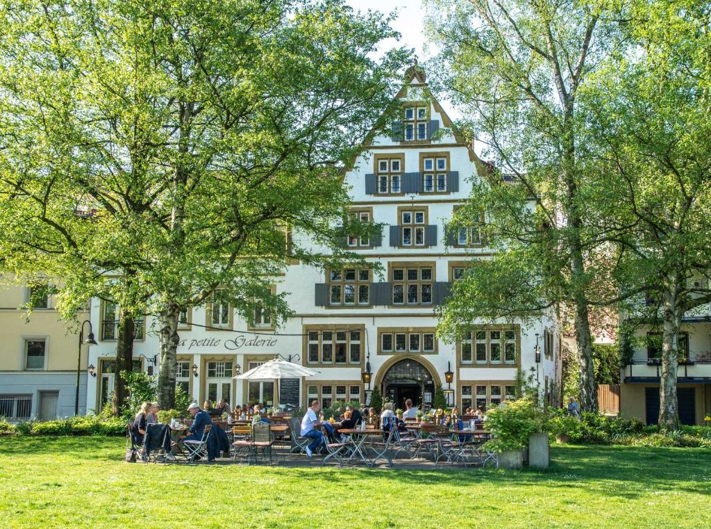 eine Gruppe von Menschen, die vor einem Gebäude sitzen in der Unterkunft Galerie Hotel in Paderborn