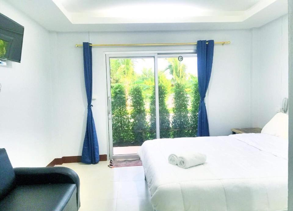 a bedroom with a bed and a window with blue curtains at Valee home & food in Nakhon Nayok