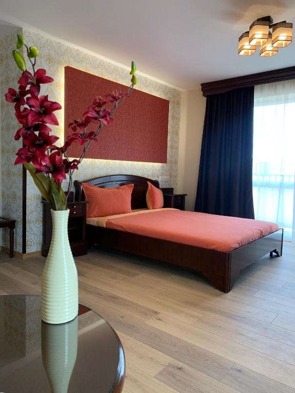 a bedroom with a bed and a vase with flowers on a table at Pensiunea Junior in Cluj-Napoca