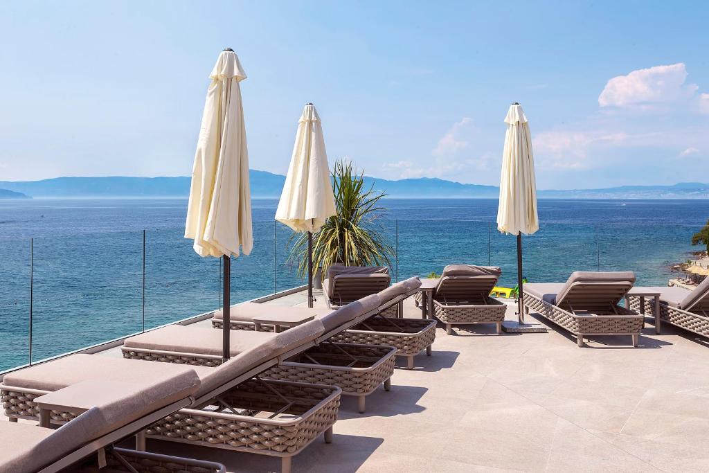 a patio with chairs and umbrellas and the ocean at Luxury Hotel Riva in Malinska