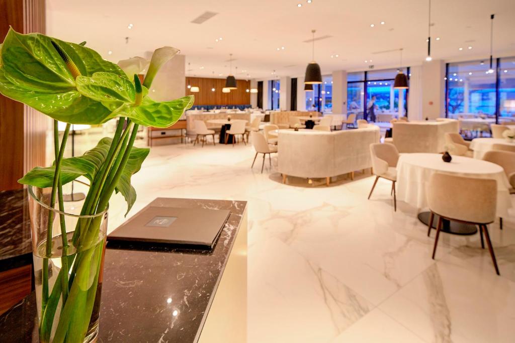 a vase with a plant on a table in a restaurant at Luxury Hotel Riva in Malinska