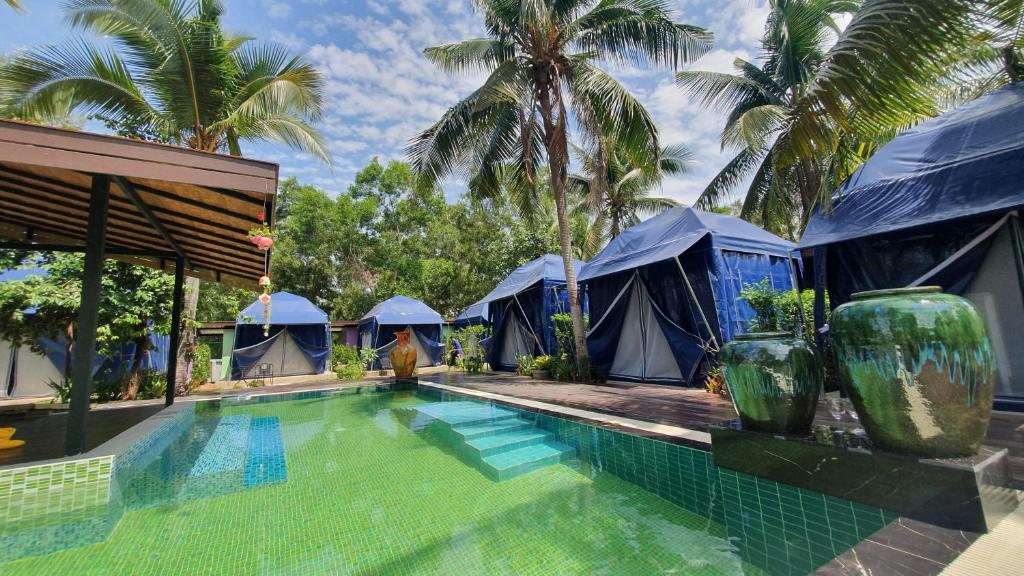 un complexe avec une piscine et des tentes bleues dans l'établissement Moonshine Resort Chumphon, à Chumpon