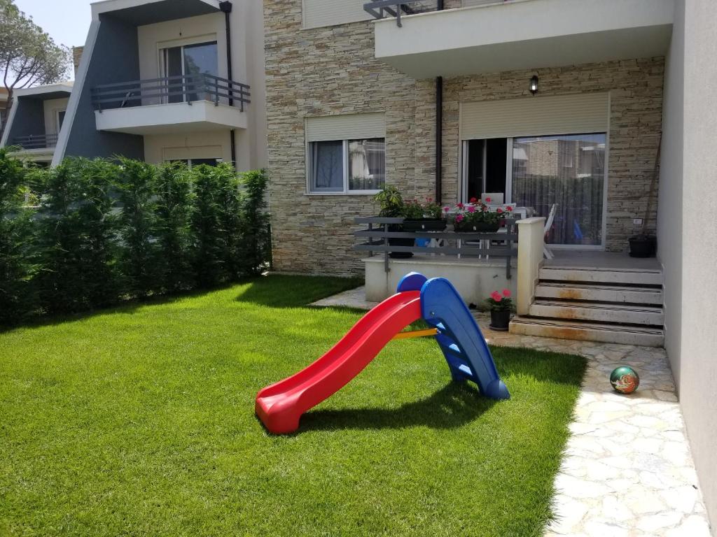 eine rote Rutsche in einem Garten vor einem Haus in der Unterkunft Beach Garden Home, Lalzi Bay in Durrës