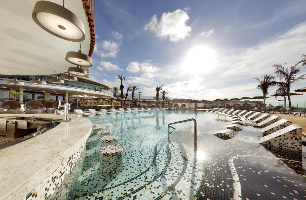 einen Pool in einem Resort mit Palmen in der Unterkunft Hard Rock Hotel Tenerife in Adeje