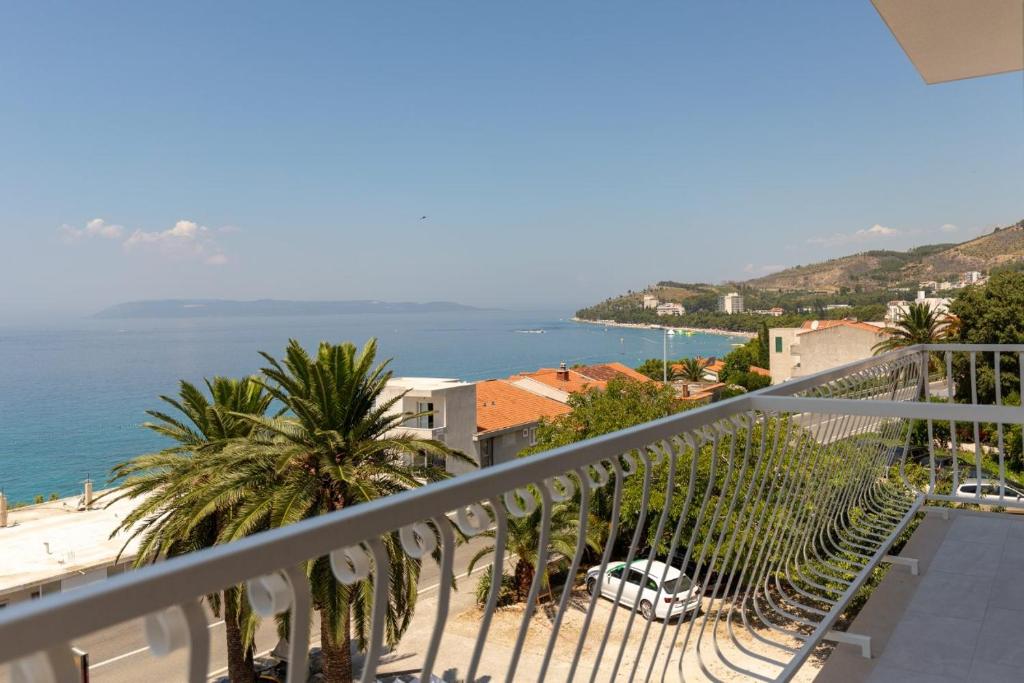 a balcony with a view of the ocean and palm trees at Mia & Ante Apartman in Tučepi