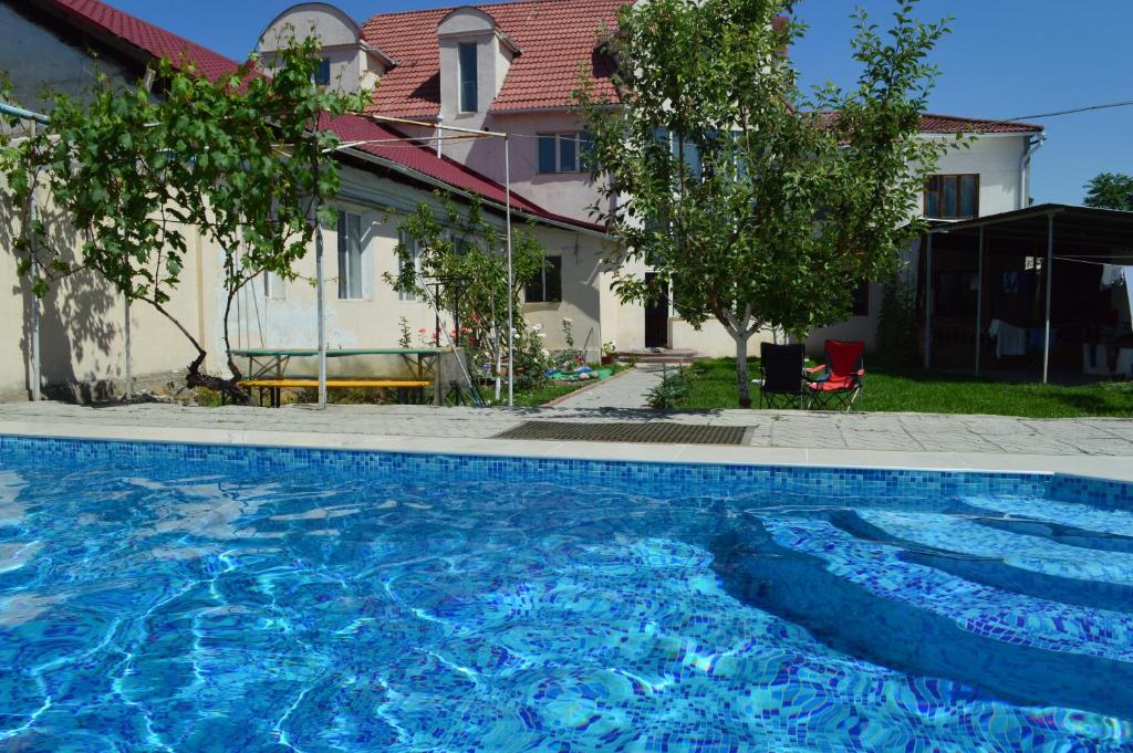 a large blue swimming pool in front of a house at Tunduk Hostel in Bishkek