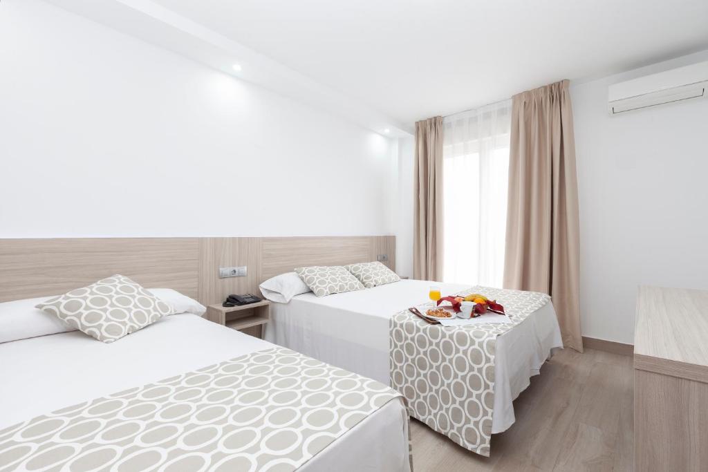 a hotel room with two beds and a table at Hotel Olympia Ronda II in El Puig