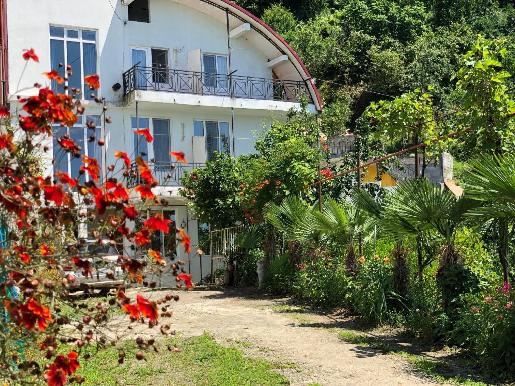 una casa blanca con flores rojas delante en Sanni Guest House, en Kvariati