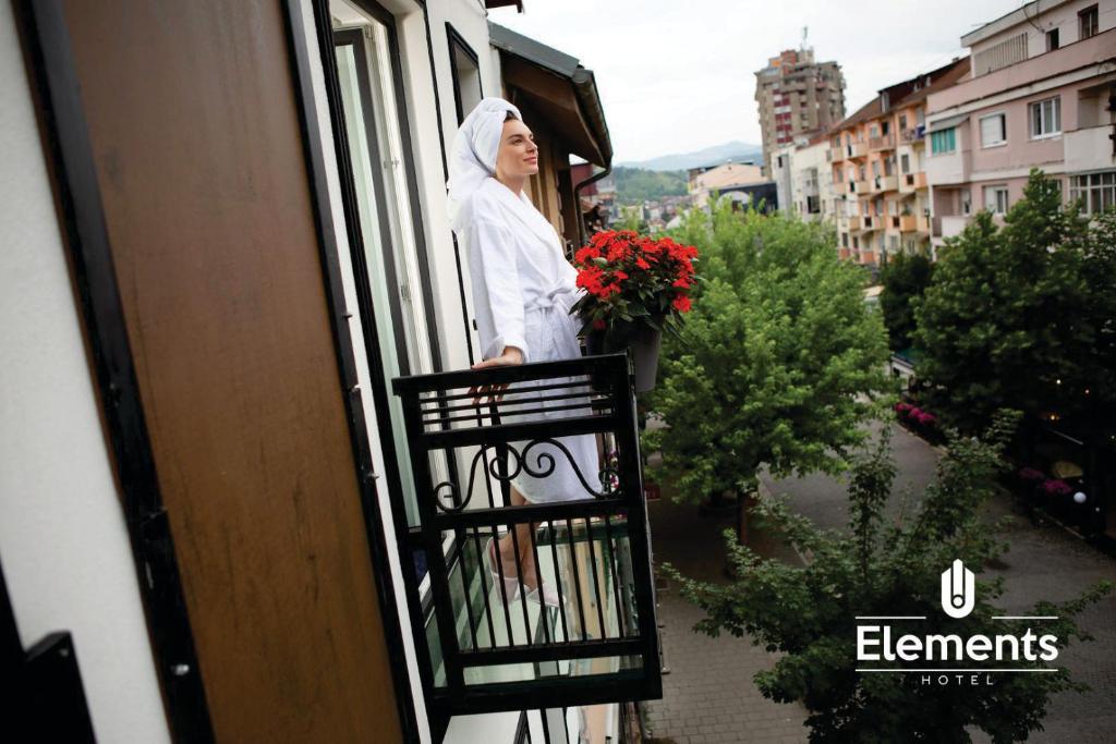 Eine Frau steht auf einem Balkon mit Blumen. in der Unterkunft Hotel Elements in Novi Pazar