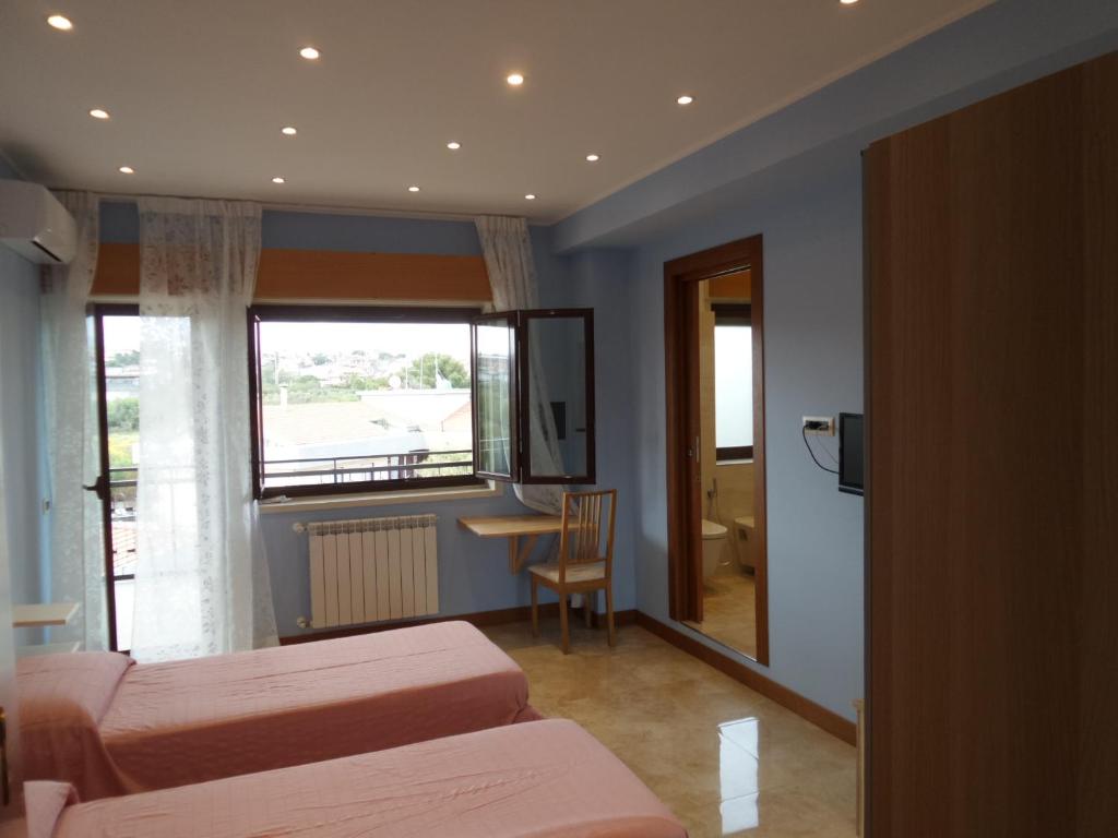 a room with two beds and a table and a window at b&b aurora in Gravina di Catania