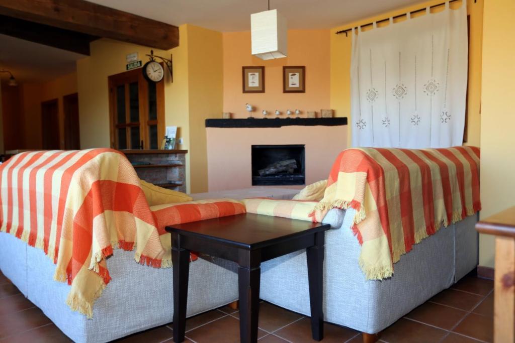 een woonkamer met 2 banken en een tafel bij Casa Rural La Casa de la Herrería in Vega del Cadorno