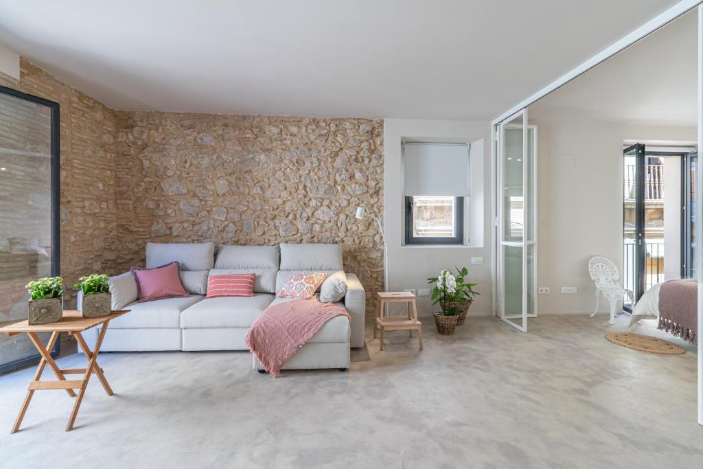 ein Wohnzimmer mit einem weißen Sofa und einer Steinmauer in der Unterkunft APARTAMENTS JONQUERA, 18 in Figueres
