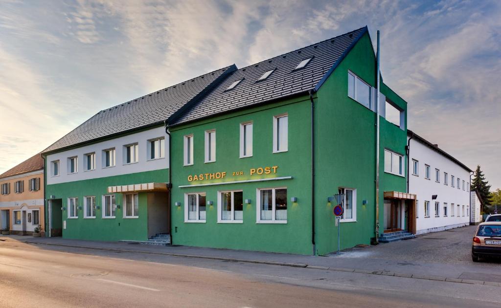 een groen en wit gebouw aan de straatkant bij Hotel Zur Post in Illmitz