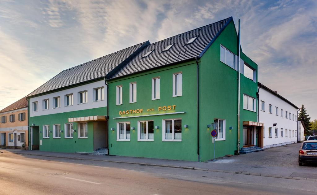 ein grün-weißes Gebäude an der Straßenseite in der Unterkunft Hotel Zur Post in Illmitz