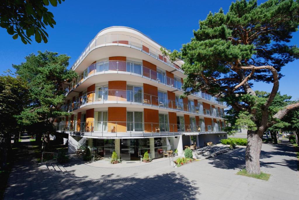 a large building with a tree in front of it at Baltic Inn in Palanga