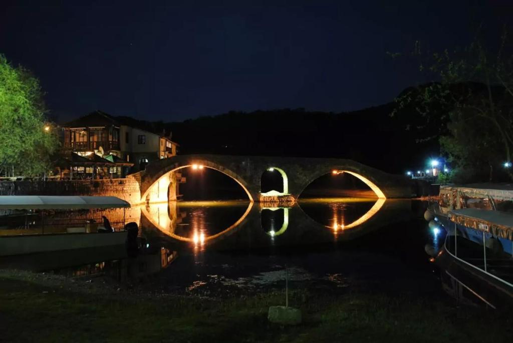 un puente de piedra con luces en el agua por la noche en Rijeka Crnojevića, Lidija Apartment en Rijeka Crnojevića