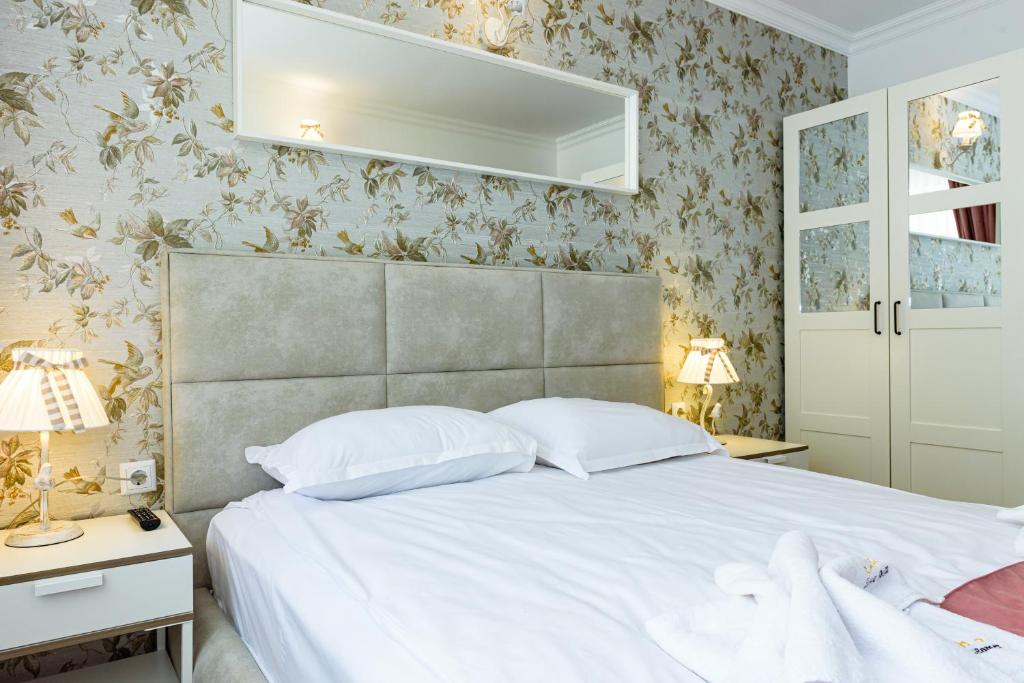 a bedroom with a white bed and floral wallpaper at Sweet Homes Apartments in Sunny Beach