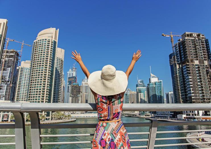 a woman in a hat standing in front of a city at AL MARSA in Dubai