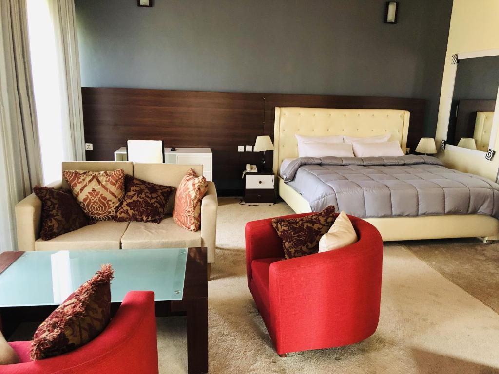 a bedroom with a bed and a couch and chairs at EZRA BOUTIQUE Hotel By The Weekender Ltd in Kigali