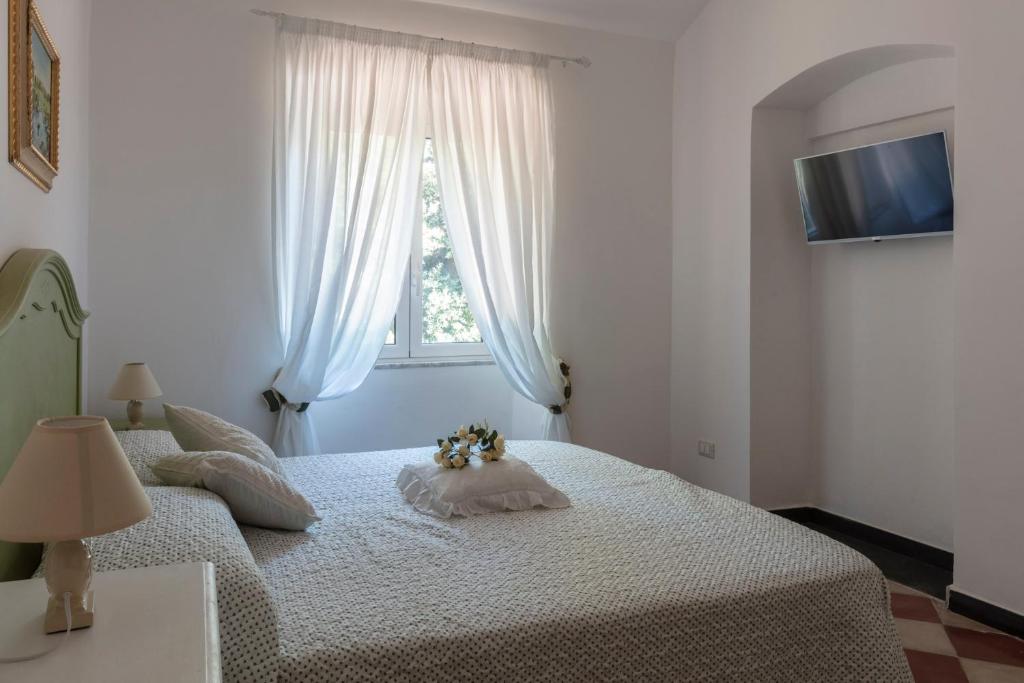 a white bedroom with a bed with flowers on it at La BRIGNA B&B Il bosco sul mare in Genoa