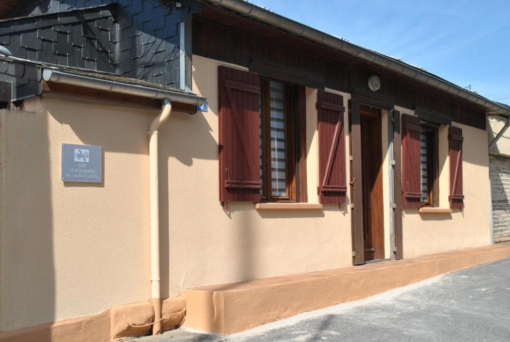un edificio con ventanas rojas y un cartel en él en GÎTE Le Moulineau en Deville