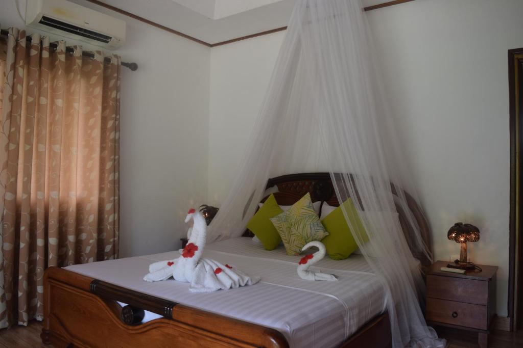 a bedroom with a bed with two swans on it at Chalet Bamboo Vert in La Digue