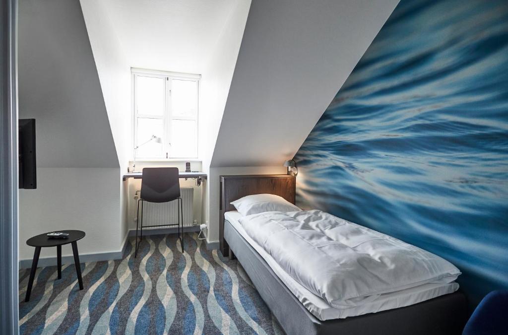 a bedroom with a bed with a painting on the wall at Vejlsøhus Hotel and Conference Center in Silkeborg