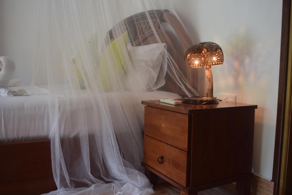 - une chambre avec un lit et une lampe sur une commode dans l'établissement Chalet Bamboo Vert, à La Digue