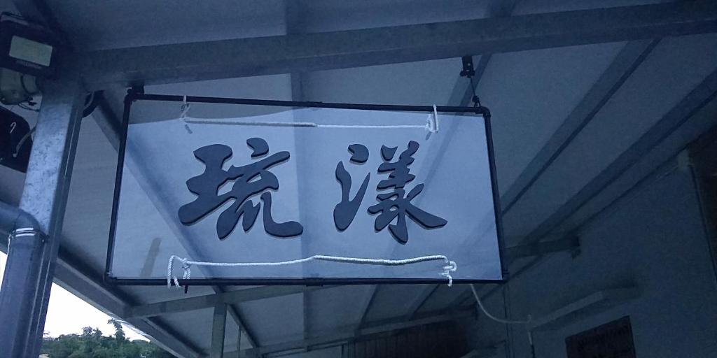 a sign hanging from a building with asian writing on it at 琉漾民宿 in Xiaoliuqiu