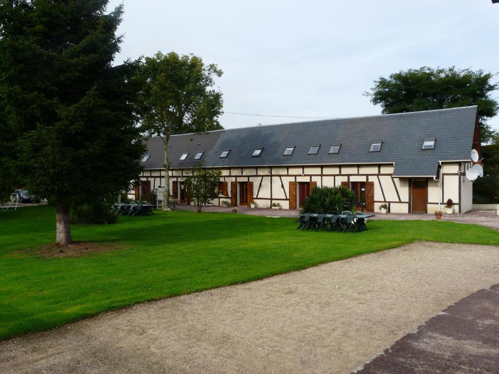 un edificio con un grupo de mesas de picnic delante de él en Chambres d'hôte du Domaine de la Reine Blanche, en Criquetot-sur-Longueville