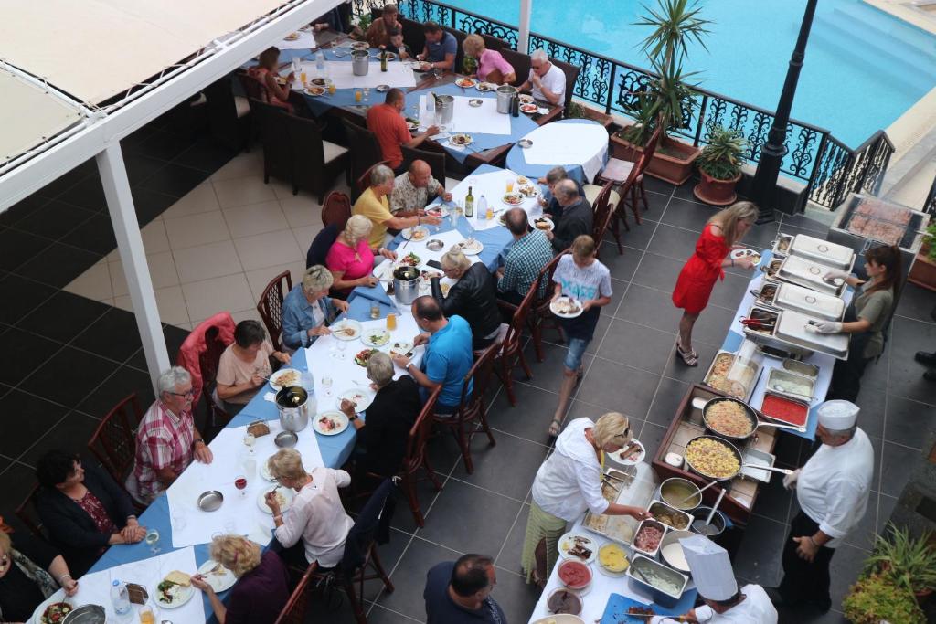 grupa ludzi siedząca przy stołach w restauracji w obiekcie Diogenis Blue Palace w mieście Guwes