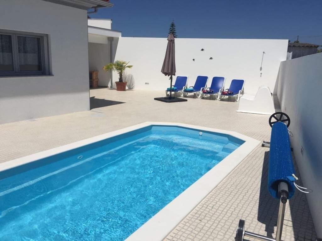 a swimming pool in a yard with chairs and an umbrella at Casa Luna in Pataias