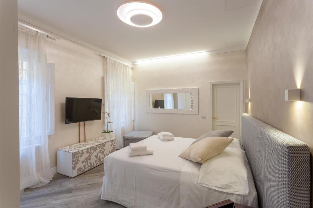 ein weißes Schlafzimmer mit einem Bett und einem TV in der Unterkunft DUOMO SUITE GHIRLANDAIO in Florenz