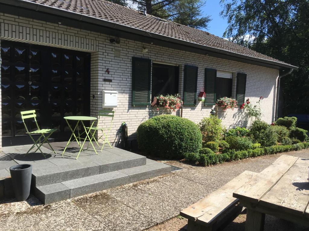 uma casa com duas cadeiras e uma mesa em frente em Ferienhaus Schils Zur alten Heidegärtnerei em Bispingen
