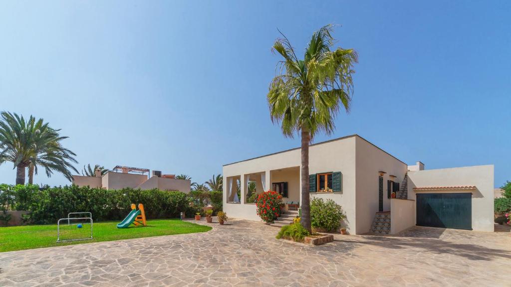 una casa con una palmera y un parque infantil en Casa Antonio Sea View en Cala Santanyi