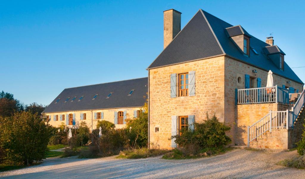 a large brick building with a black roof at La Riviere Esperance in Veyrignac