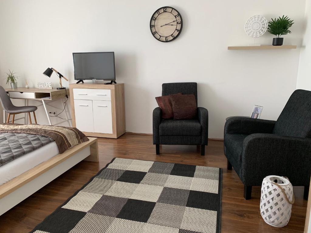 a bedroom with a bed and a chair and a tv at Liliom Apartman Pécs in Pécs