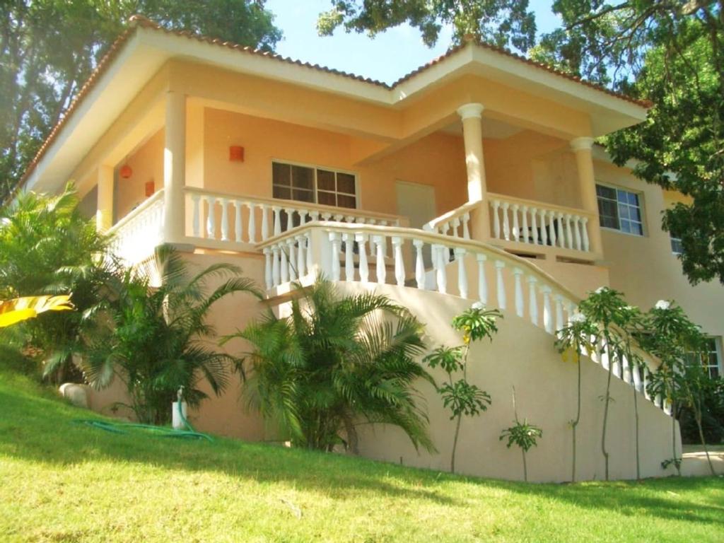 una casa con balcón y palmeras frente a ella en VillaTracey! Modern 4BR 3BA Sosua Ocean View Villa with Private Pool in Gated Community #15, en Sosúa