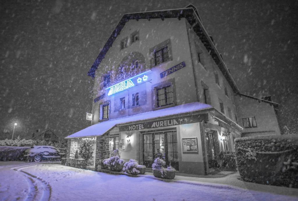 a building with a sign on it in the snow at Hôtel Aurélia in Saint-Lary-Soulan