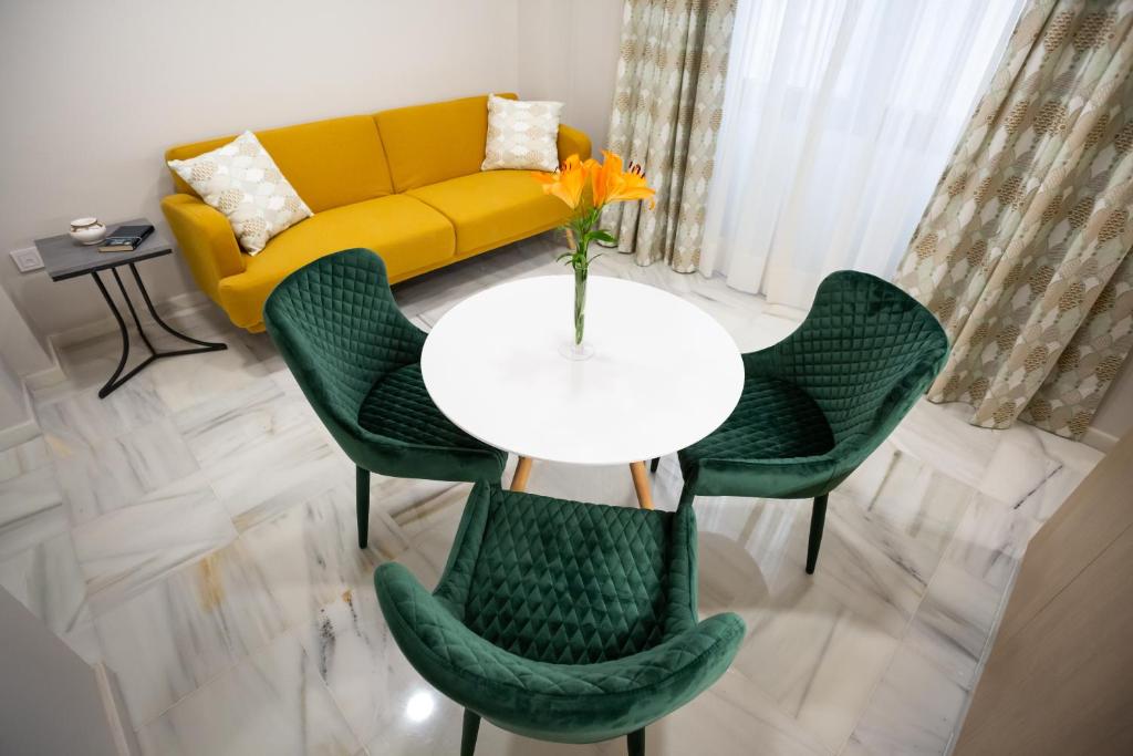 a living room with a yellow couch and a table and chairs at Plazuela del Carbón Suites in Cádiz