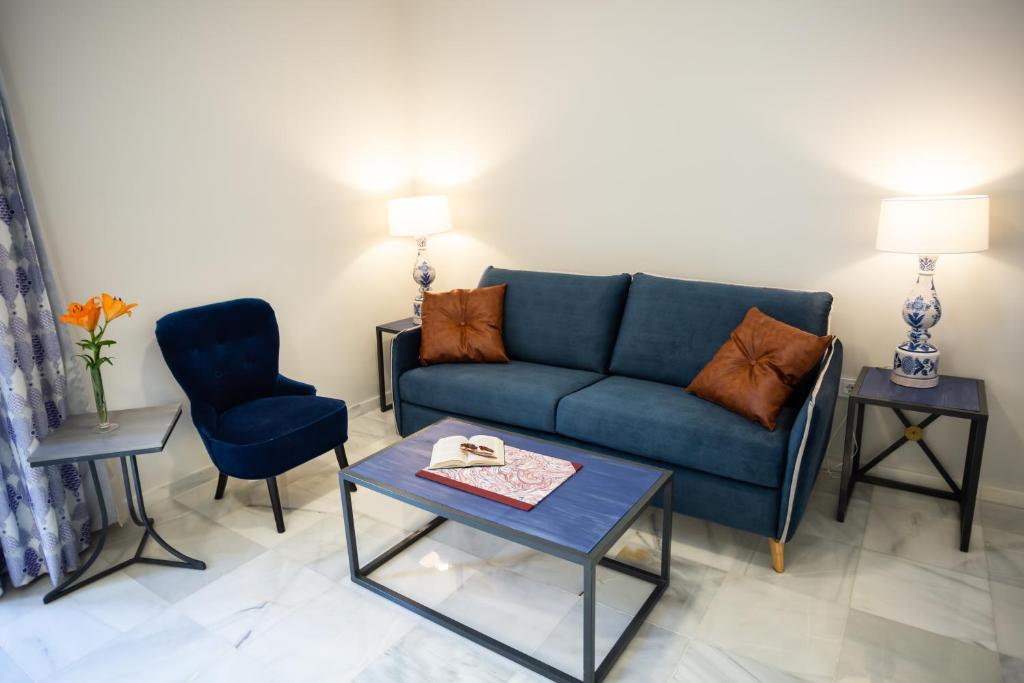 a living room with a blue couch and two chairs at Plazuela del Carbón Suites in Cádiz