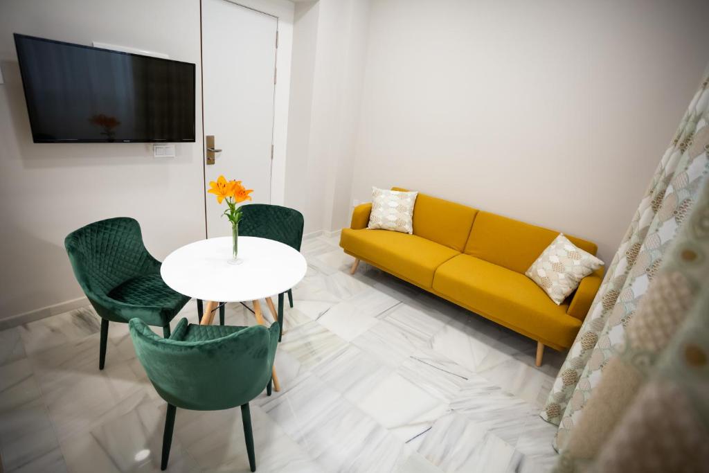 a living room with a yellow couch and a table at Plazuela del Carbón Suites in Cádiz