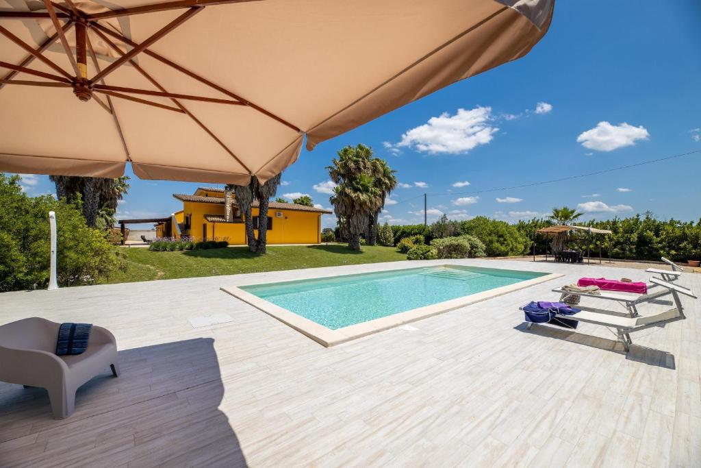 einen Pool mit Sonnenschirm und Stühlen und ein Haus in der Unterkunft Villa Esmeralda in Taviano