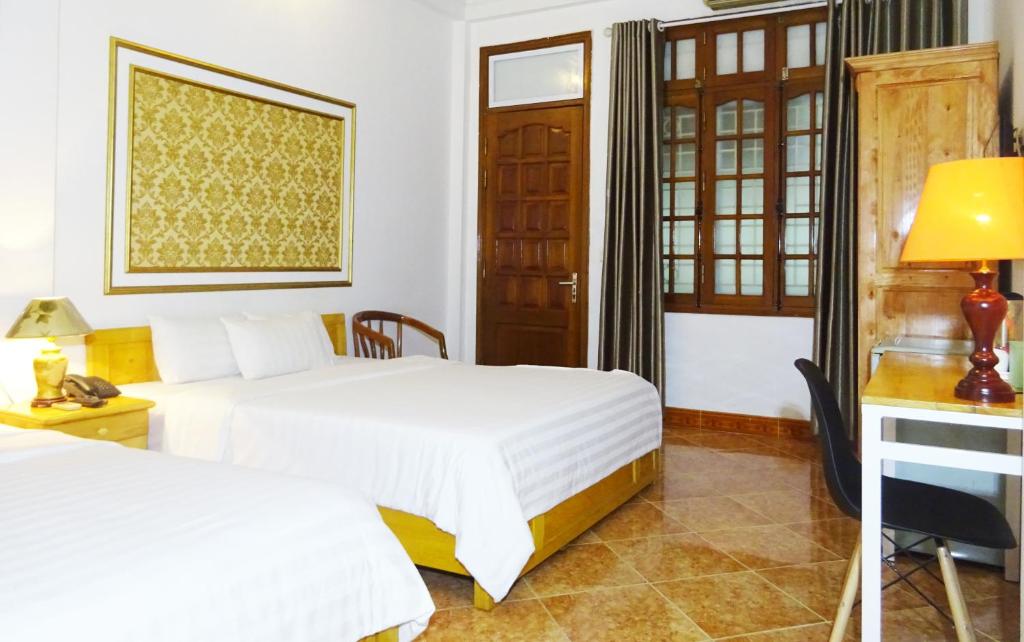 Habitación de hotel con 2 camas y escritorio en Hanoi Discovery Hotel, en Hanói