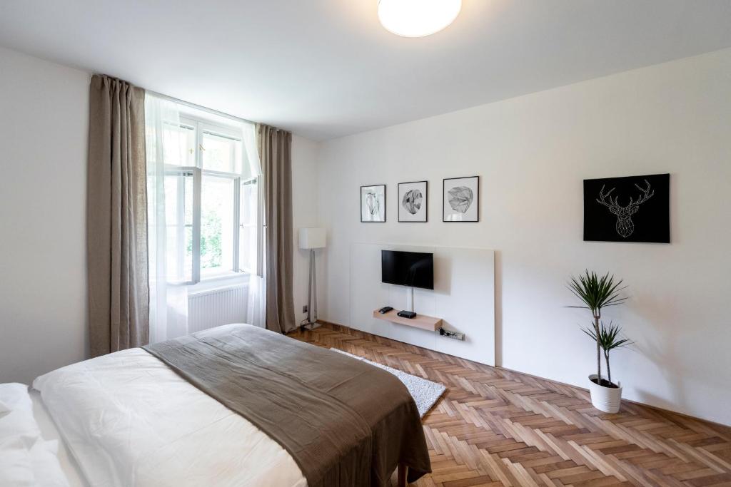 biała sypialnia z łóżkiem i telewizorem w obiekcie Apartment Slavikova 11 w Pradze